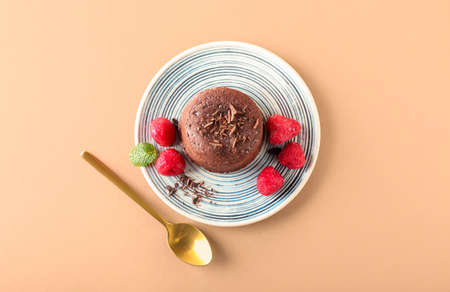 Plate with tasty lava cake fondant and raspberry on color background