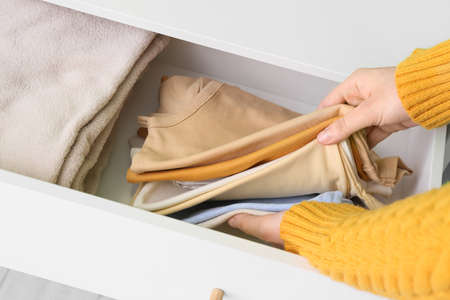 Woman taking baby clothes from drawer, closeupの写真素材