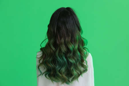 Beautiful young woman with unusual green hair on color backgroundの写真素材