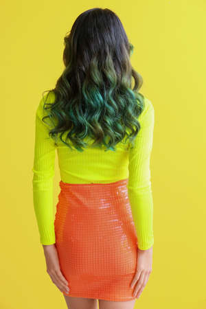 Beautiful young woman with unusual green hair on color background