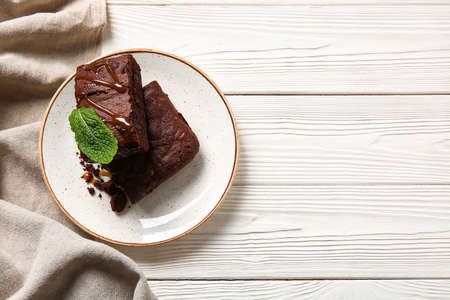 Plate with pieces of tasty chocolate brownie on white wooden backgroundの写真素材