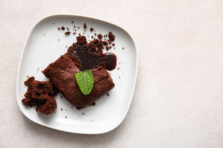 Plate with pieces of tasty chocolate brownie on white background