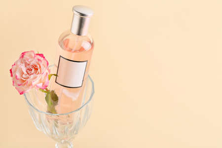 Perfume and glass with rose for Valentine's day on beige background