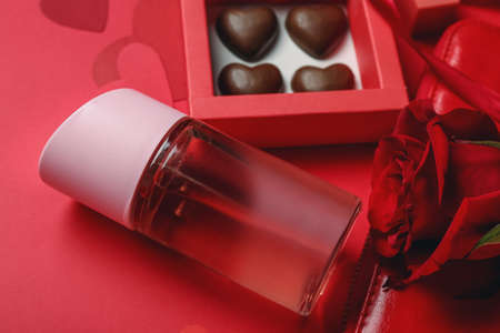 Perfume, rose and chocolate candies for Valentine's day on red background, closeupの写真素材