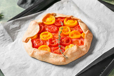Baking tray with tasty tomato galette on table, closeup