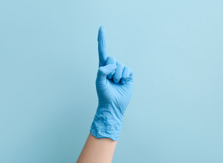 Female doctor in medical glove pointing at something on blue backgroundの写真素材