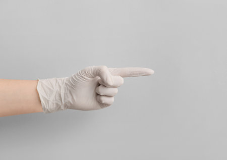 Woman in medical glove pointing at something on light backgroundの写真素材