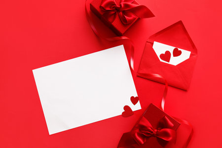 Composition with blank card, envelope and gifts for Valentine's Day on red background
