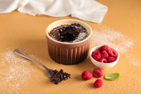 Ramekin with tasty lava cake and raspberries on color backgroundの写真素材