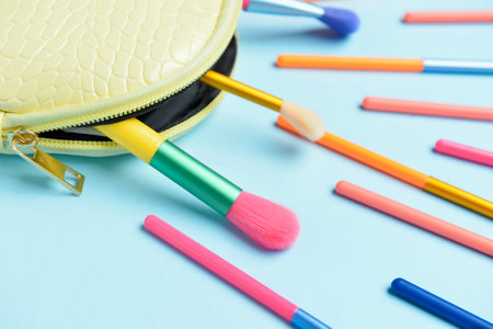 Cosmetic bag with set of colorful makeup brushes on blue background, closeupの写真素材