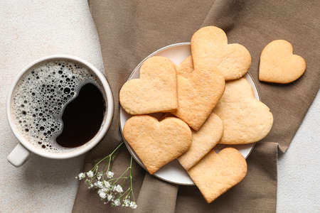 Plate with tasty heart shaped cookies and cup of coffee on white background. valentine's day...