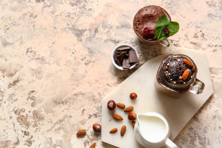 Mason jar and glass cup with tasty chocolate brownie on beige backgroundの写真素材