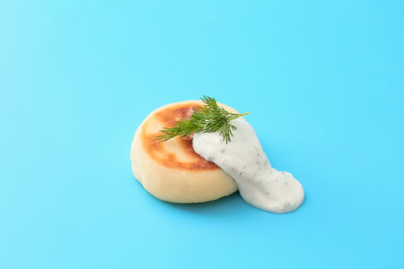 Tasty cottage cheese pancake and sauce on blue background