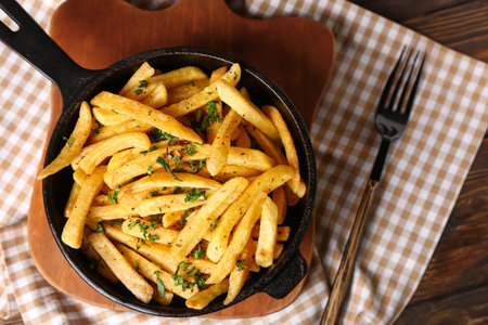 Frying pan with tasty french fries on table