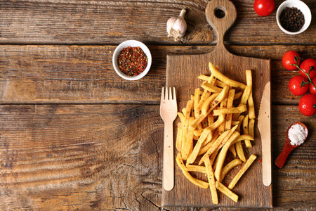 Board with tasty french fries on wooden backgroundの写真素材