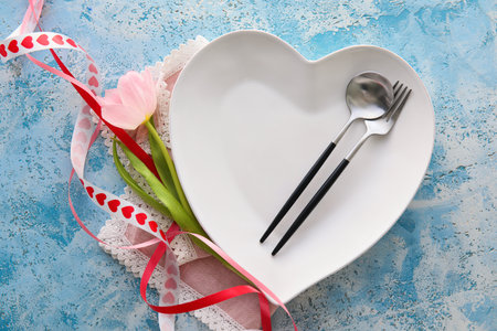 Beautiful table setting for Valentine's Day and tulip flower on blue grunge backgroundの写真素材