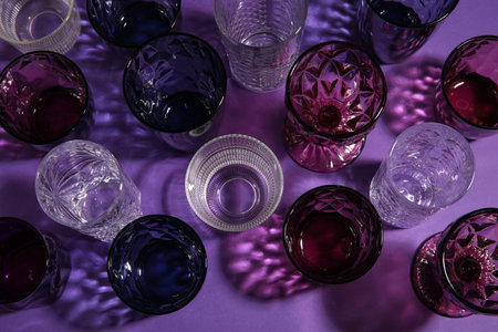 Different empty glasses on purple background, top viewの写真素材