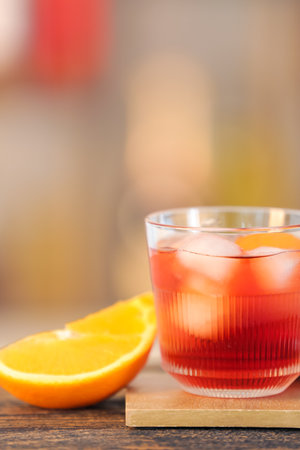 Glass of tasty Negroni cocktail on table against blurred background