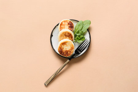 Plate with tasty cottage cheese pancakes on color background
