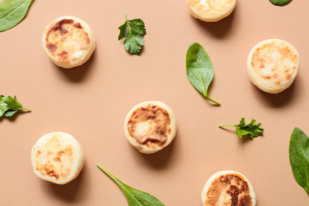 Tasty cottage cheese pancakes and greens on color background