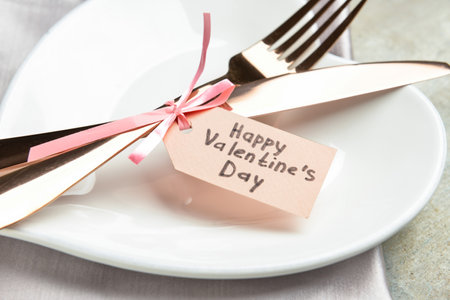 Beautiful table setting and tag with text HAPPY VALENTINE'S DAY on grunge background, closeupの写真素材