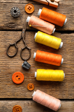Sewing threads with buttons and scissors on wooden background