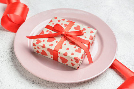 Beautiful plate and gift box on white background