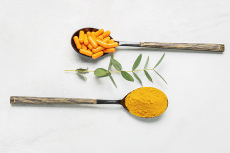 Spoons with turmeric capsules and powder on light backgroundの写真素材