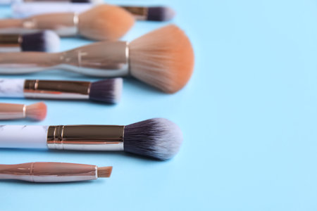 Set of beautiful makeup brushes on blue background, closeup