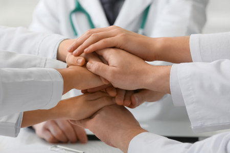 Group of doctors putting hands together in clinic, closeupの写真素材