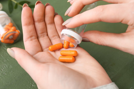 Female hands with turmeric powder capsules, closeupの写真素材