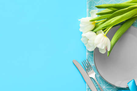 Stylish table setting with tulip flowers on blue backgroundの写真素材