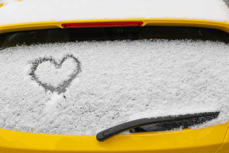 Heart drawn on snow covered car rear window on street, closeupの写真素材