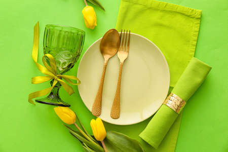 Stylish table setting with tulip flowers on green backgroundの写真素材