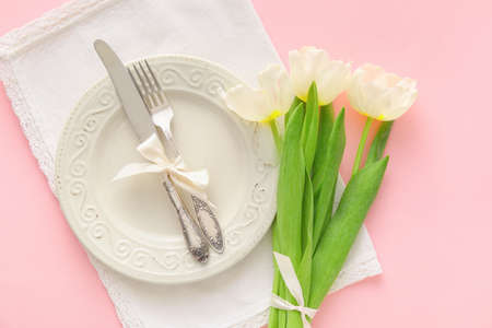 Stylish table setting with tulip flowers on pink backgroundの写真素材