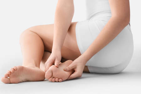 Young woman making foot massage on light background, closeupの写真素材