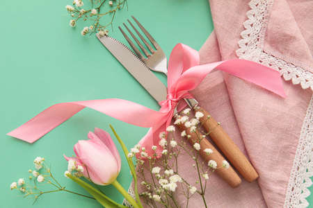 Stylish cutlery with beautiful flowers on turquoise background
