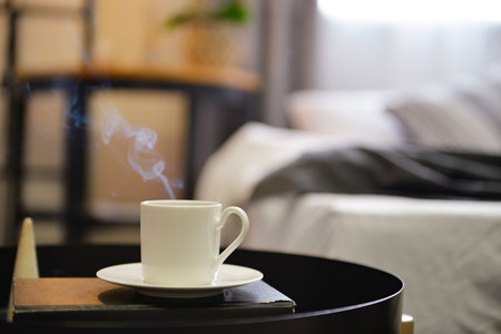 Cup of hot coffee with book on table in bedroom, closeupの写真素材