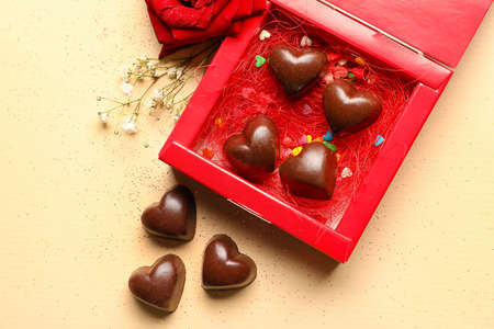 Box with tasty heart-shaped candies on beige background