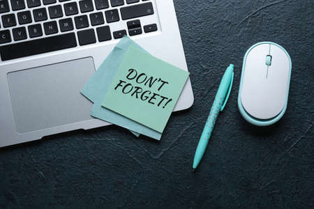 Laptop, paper with text DON'T FORGET and pen on dark backgroundの写真素材