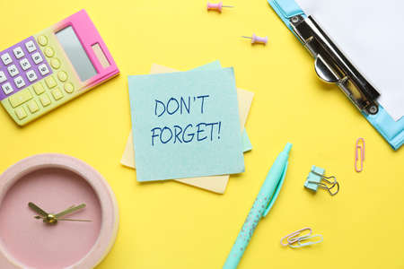 Paper with text DON'T FORGET, clock and stationery on yellow backgroundの写真素材