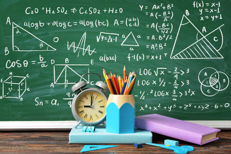 Set of school supplies and clock on table in classroom. Time to study