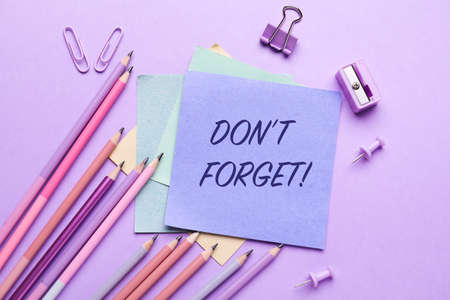 Paper with text DON'T FORGET, pencils and stationery on lilac backgroundの写真素材