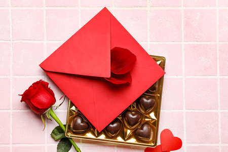 Box with tasty heart-shaped candies and roses on color backgroundの写真素材