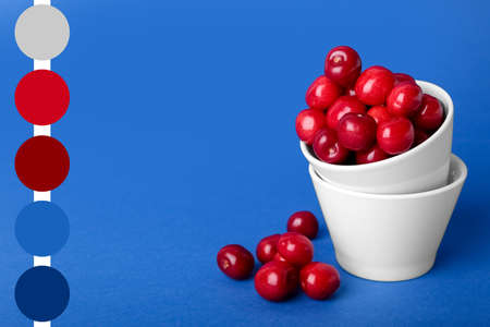Bowls with sweet cherries on blue background. different color patternsの写真素材