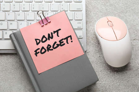 Notebook, paper with text DON'T FORGET and computer on gray backgroundの写真素材