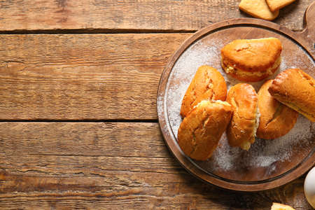 Board of tasty sochniki with cottage cheese on wooden background
