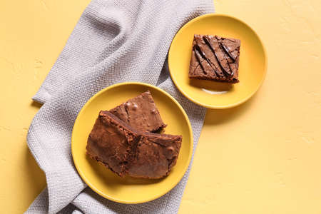 Plates with pieces of tasty chocolate brownie on yellow backgroundの写真素材