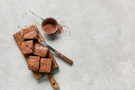 Wooden board with pieces of tasty chocolate brownie on light backgroundの写真素材