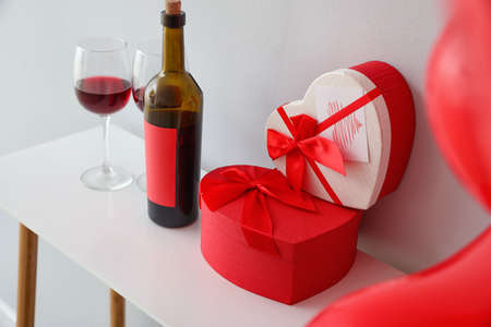 Gifts for Valentine's Day and red wine on table in room